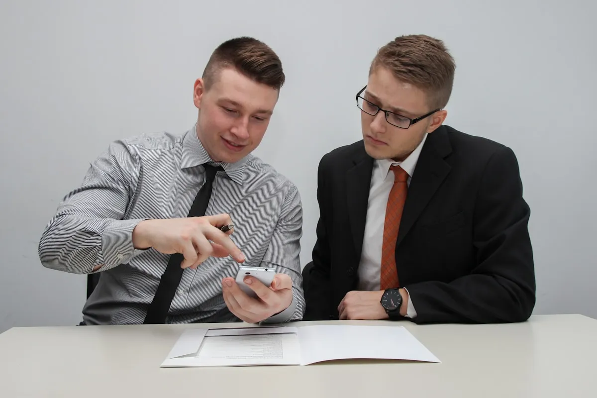Two men reviewing financial information on a smartphone, representing collaborative retirement planning decisions