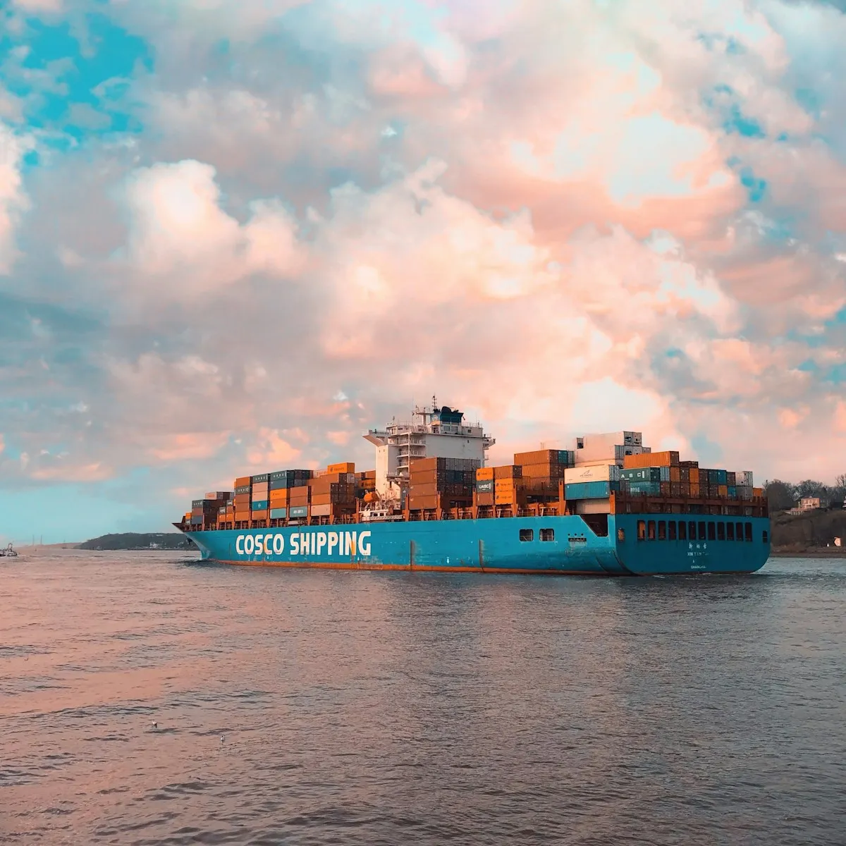 Blue cargo ship navigating open waters, representing the global trade routes vulnerable to geopolitical disruption