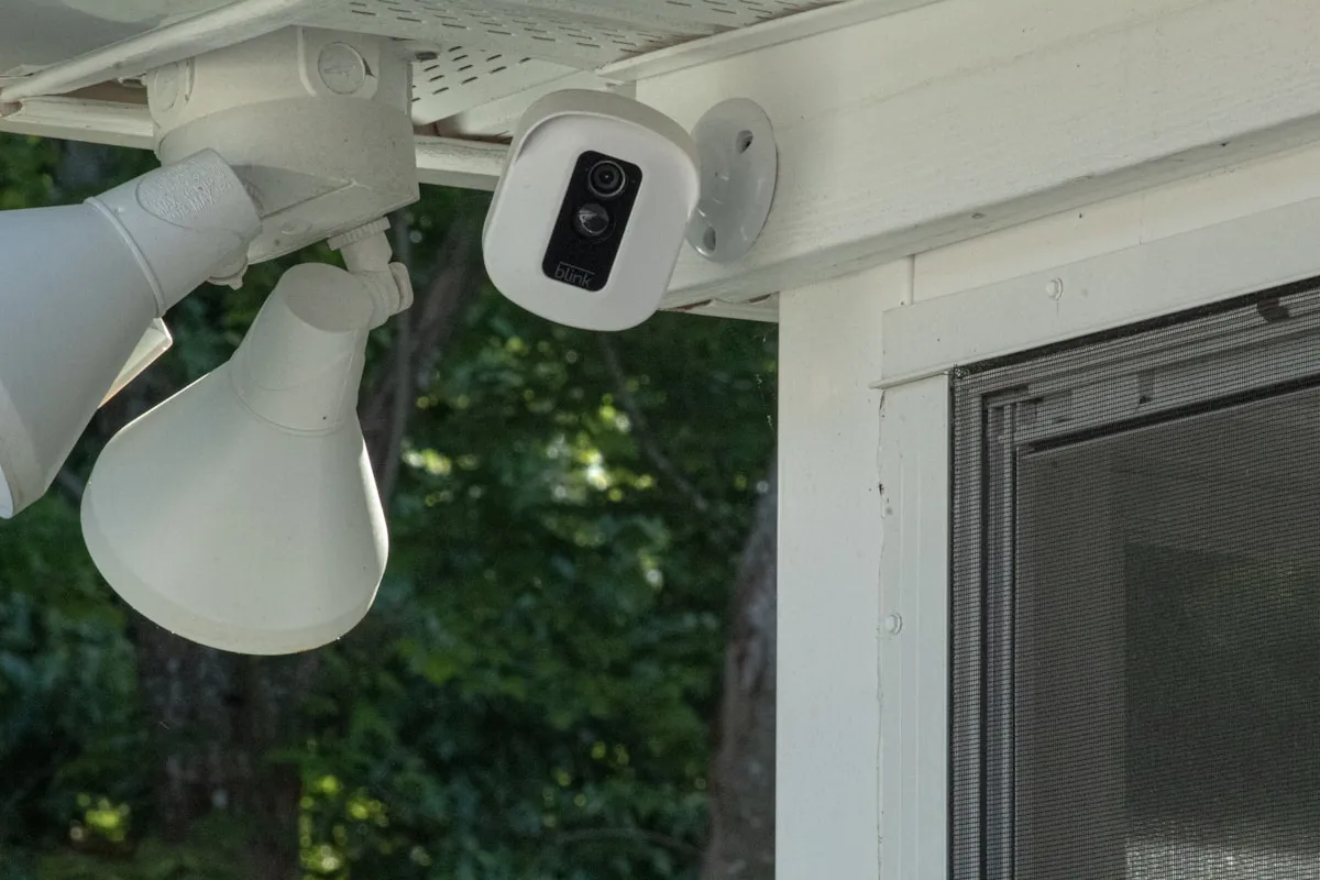 A white and black security camera mounted on a wall, representing the vigilance and security planning needed for gold holdings