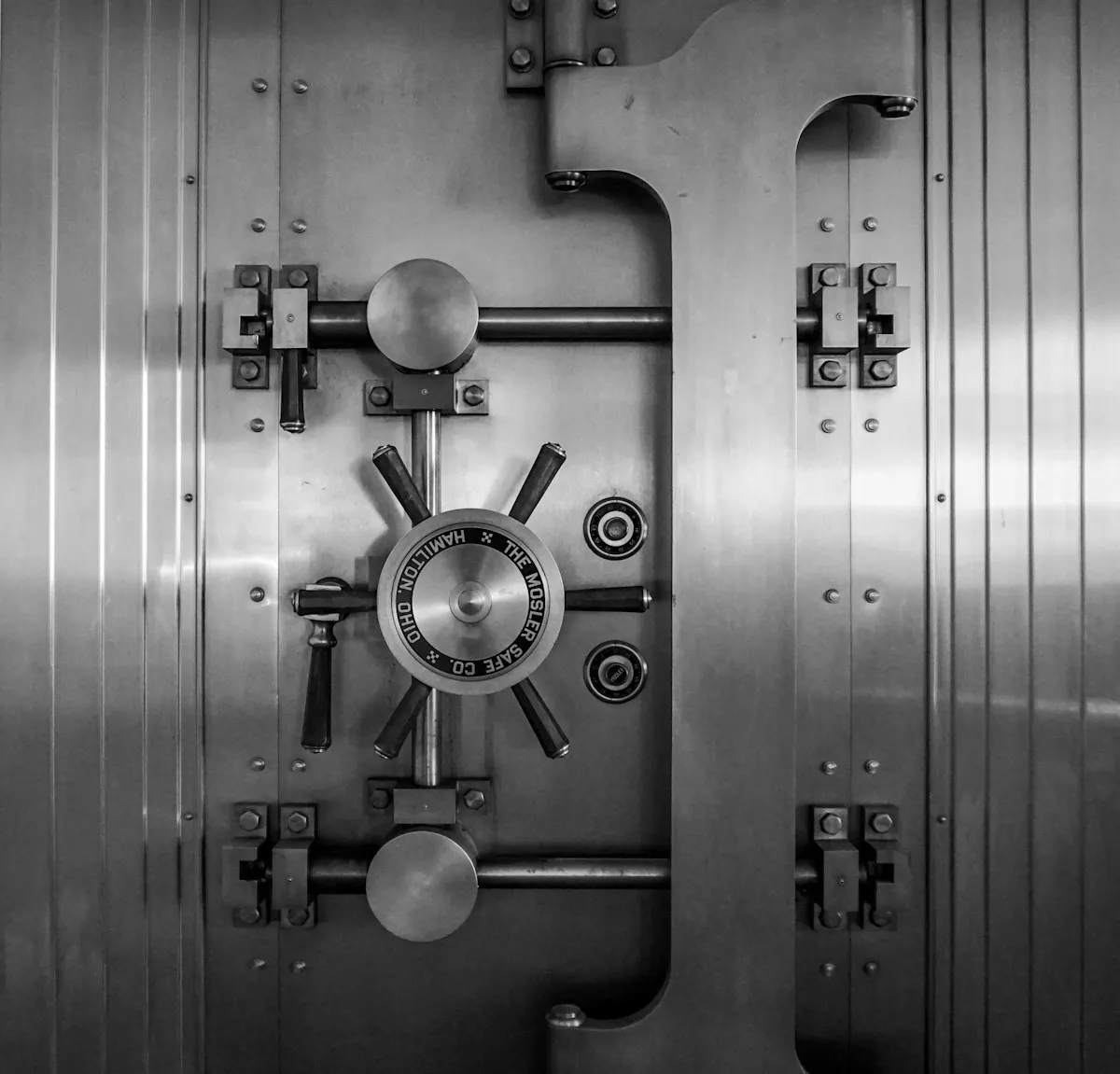 A heavy gray steel vault door, representing the institutional-grade security infrastructure that protects precious metals in professional depositories