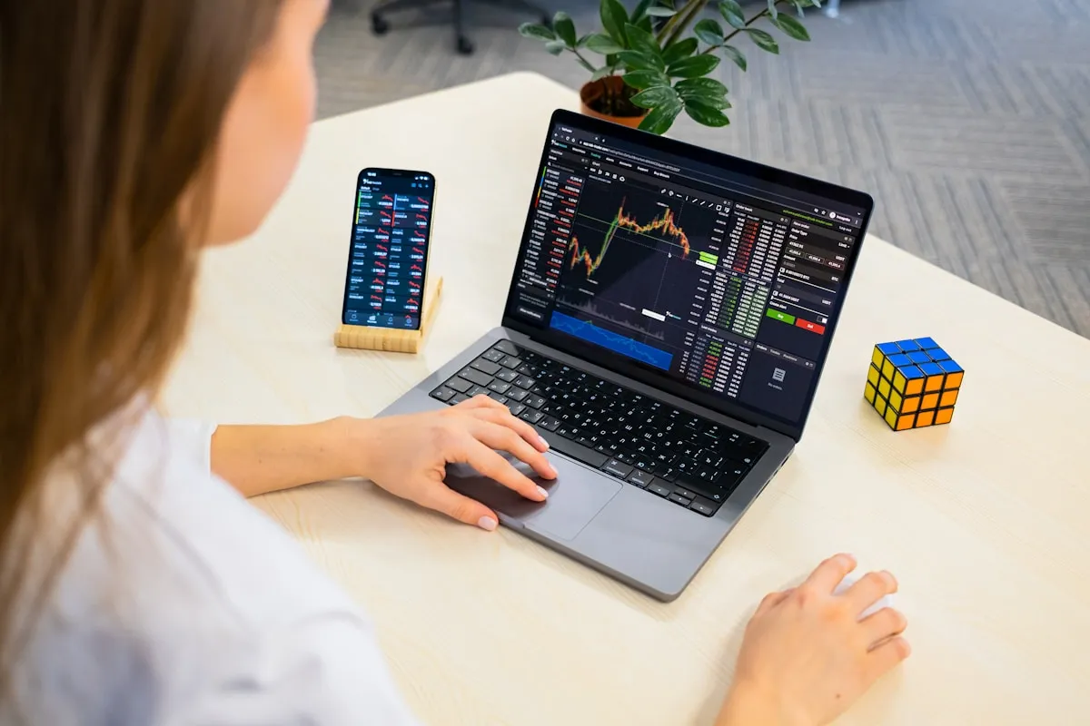 Woman researching gold market data on a laptop, analyzing price charts and timing indicators