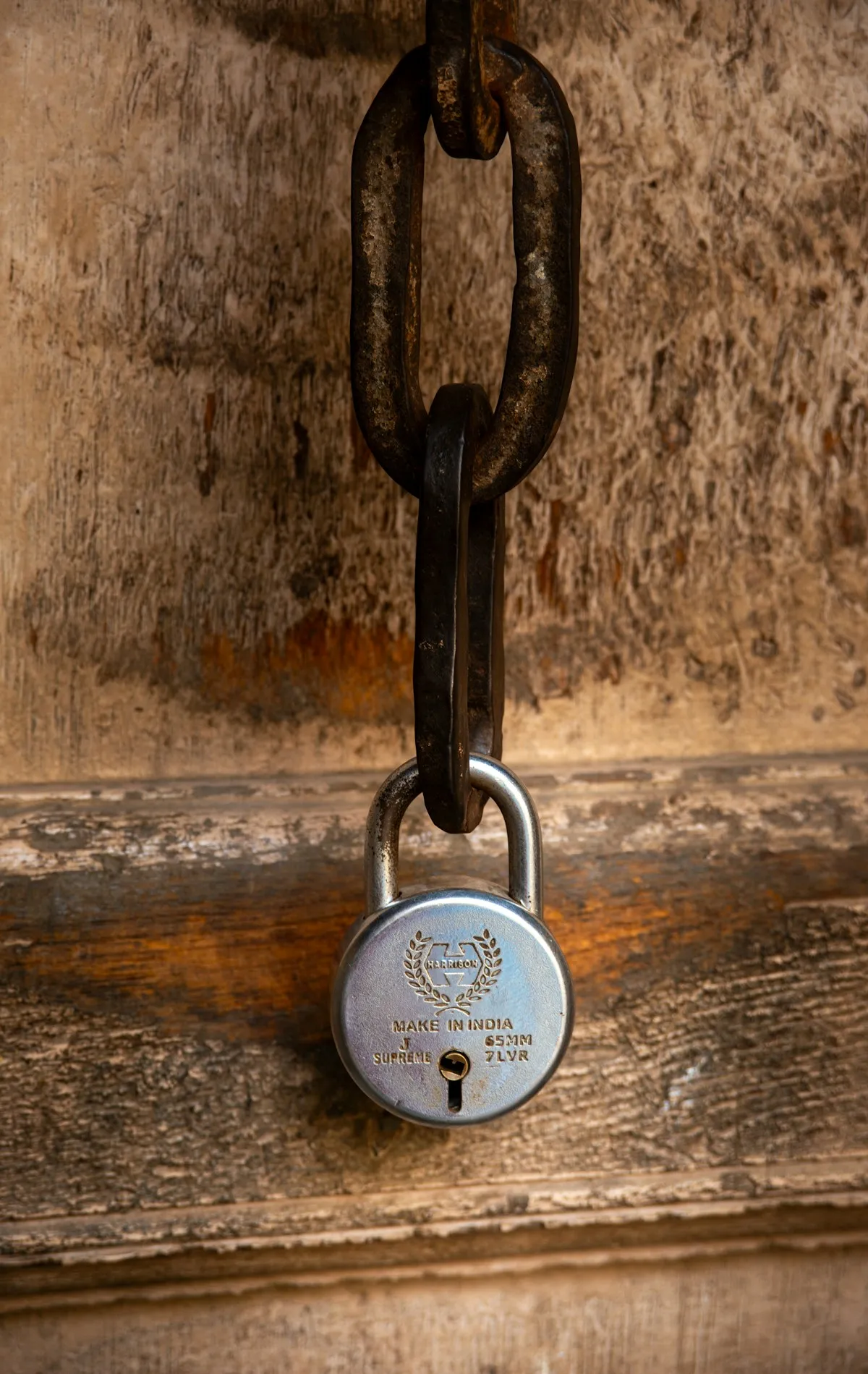 An old rusty chain and padlock securing a gate, the visible presence of security signals difficulty, even when the real protection lies hidden elsewhere